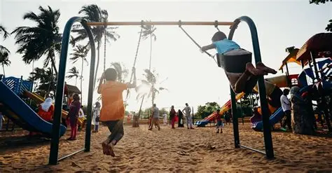 Two young children laughing together on a swing set