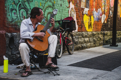 A street musician playing guitar in an urban alleyway
