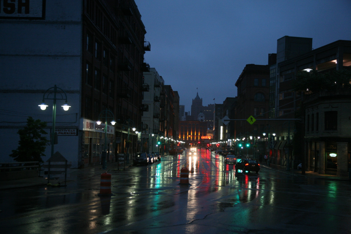 A rain-soaked city street at night with neon signs reflecting in puddles