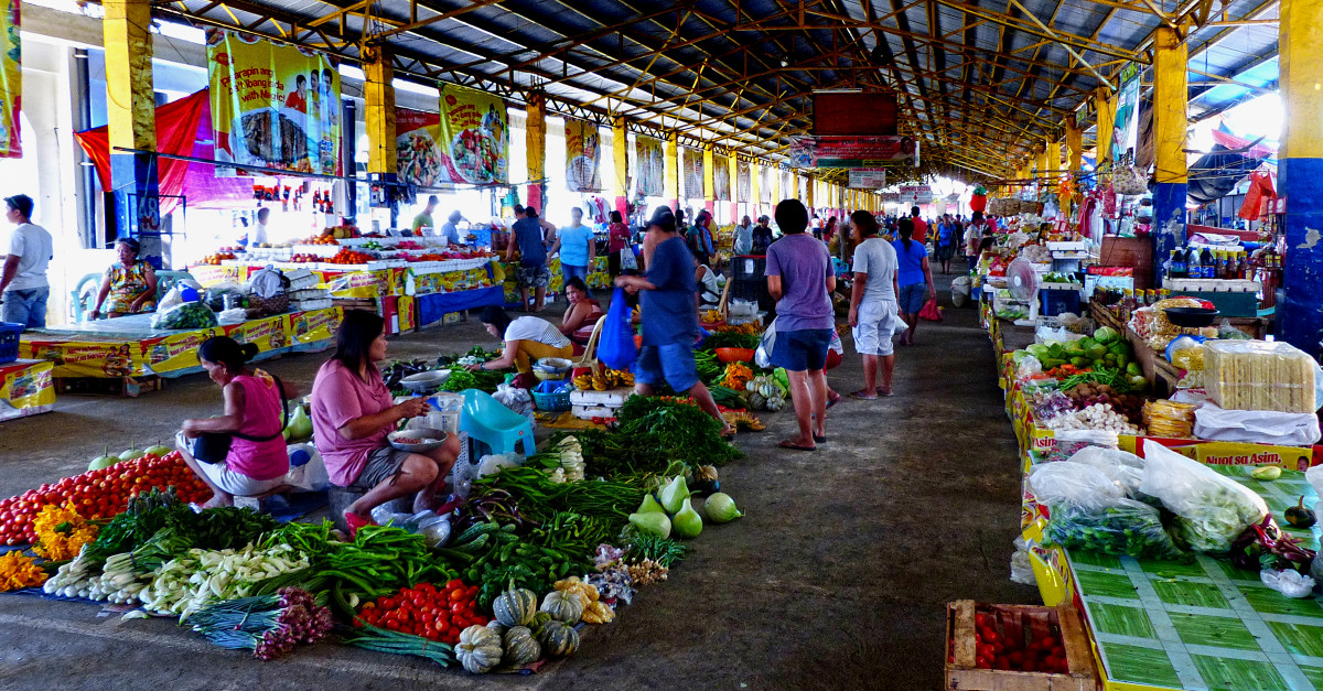 A busy outdoor farmers market with colorful produce stalls